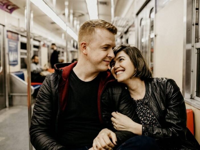 Casal sorrindo no metrô abraçados, mas preocupados com infertilidade