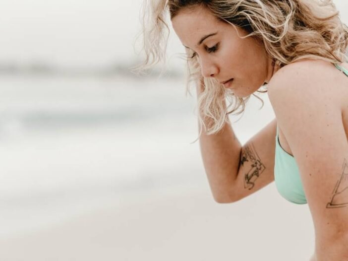 Mulher na praia com ar preocupado pelas dores da endometriose