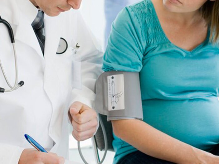 Médico obstetra atende gestante em consultório medindo sua pressão