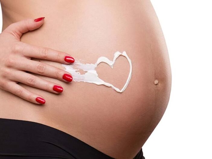Como evitar Estrias na Gravidez, gravida com coração feito com creme na barriga