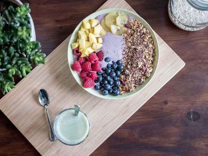 Prato com comida saudável sobre tábua de madeira numa mesa com brócolis ao lado