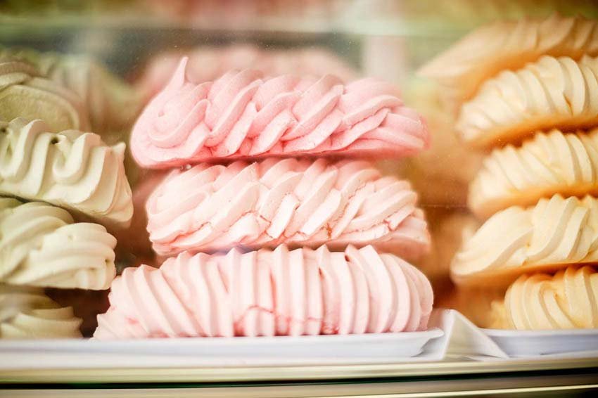 Doces de suspiro coloridos empilhados em tons de rosa, amarelo e bege