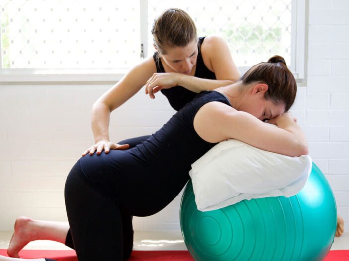 Gestante faz exercício de postura com fisioterapeuta